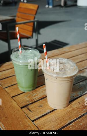 Two iced drinks, green and coffee-colored, on a wooden outdoor table, California Stock Photo