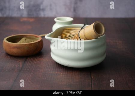 Mixing matcha in a traditional bowl with utensils nearby Stock Photo