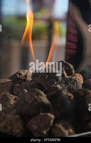 Flames dance above rocks in an outdoor setting Stock Photo