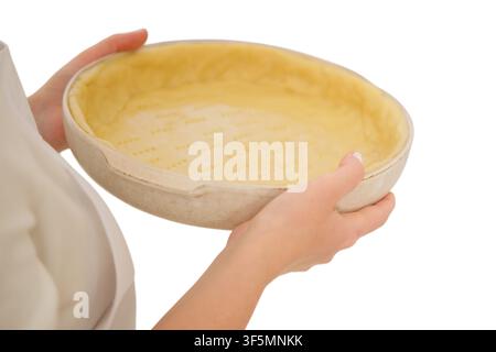 Woman baker holding ceramic tart pan with raw shortcrust pastry dough. Culinary preparation for homemade pie. Cooking process in kitchen. Raw food ing Stock Photo