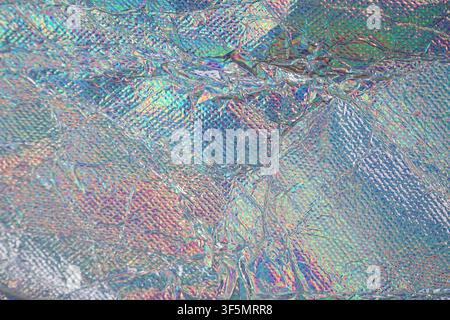 Macro view of wrinkled holographic material featuring rainbow reflections and metallic texture for futuristic designs. Stock Photo