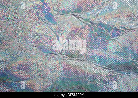 Abstract iridescent background with crumpled holographic foil texture and rainbow shimmer. Stock Photo