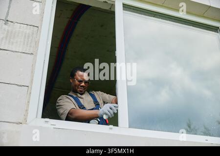 Black Man Installing New Window during House Renovation Stock Photo