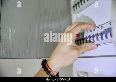 Hand of Man Switching Circuit Breaker during House Renovation Stock Photo