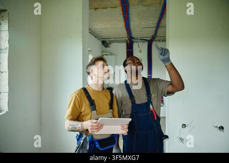 Diverse Male Builders Planning House Renovation Using Digital Tablet Stock Photo