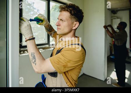 Man Installing Window Frame during House Renovation Stock Photo