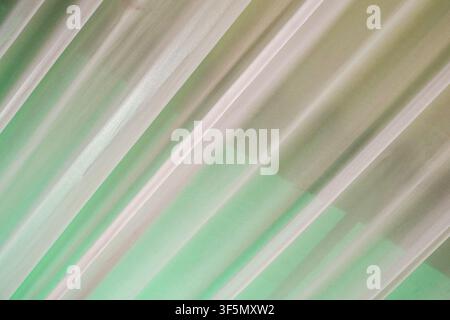 Abstract close-up of translucent green and white fabric featuring elegant diagonal pleats and folds. Ideal for soft backgrounds, interior design, or t Stock Photo