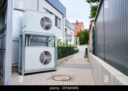Two outdoor heat pump units are installed beside a modern residential building. Energy efficient home heating equipment and residential energy infrast Stock Photo