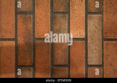 Close-up of weathered rectangular terracotta bricks with dark grout. The earthy brown and orange tones provide a rustic, industrial texture suitable f Stock Photo