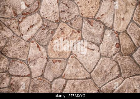 Textured stone pavement with beige irregular rocks and grey mortar for construction or exterior design backgrounds. Stock Photo