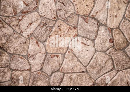 Detailed rustic stone pavement texture featuring weathered irregular rocks and dark grout for architectural backgrounds. Stock Photo