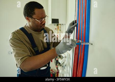 Black Man Installing Water Pipes during House Renovation Stock Photo