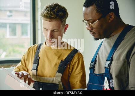 Man and Black Man Planning House Renovation Using Digital Tablet Stock Photo