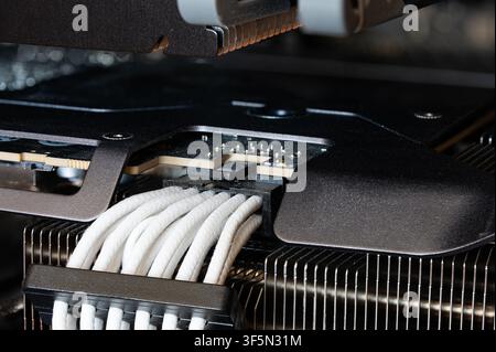Detailed macro shot of white custom sleeved PCIe power cables connected to a graphics card with metallic heatsink fins inside a custom computer case. Stock Photo