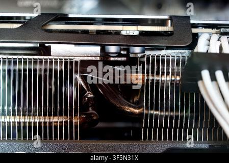 Detailed macro shot showing metallic cooling fins and copper heat pipes of a GPU heatsink alongside custom white sleeved PCIe cables inside a desktop Stock Photo