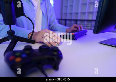 Gamer using computer mouse and keyboard at desk with controller for video gaming setup Stock Photo