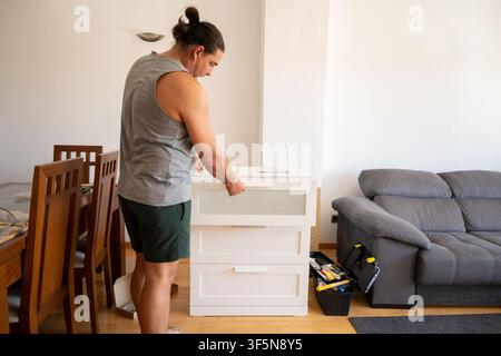 Man assembling new furniture in living room with a toolbox Stock Photo