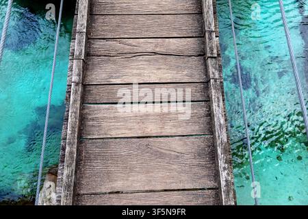 Minimalist view of old wooden footbridge boards above the turquoise Soča River in Slovenia, with clear water in the background and no people. Stock Photo