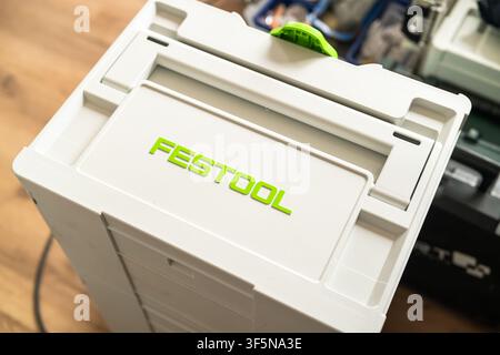PRAGUE, CZECH REPUBLIC, JUNE 2026. Storing various hand tools inside a sturdy FESTOOL white container with bright green branding at a woodworking station. Clean workspace with wooden flooring and additional toolboxes visible in the background.  Stock Photo