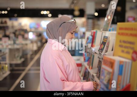 Young Muslim woman browsing books in a bright bookstore Stock Photo