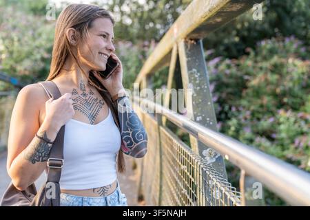 Woman smiling talking on phone walking on bridge Stock Photo