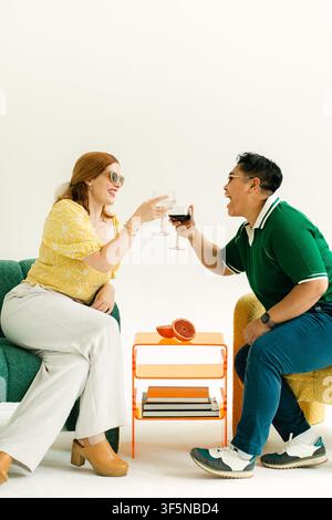 Two stylish people laugh while toasting wine Stock Photo