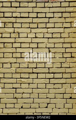 Yellow painted brick wall with neat rows and dark contrast seams. Clean architectural background featuring even masonry structure and textured brickwo Stock Photo