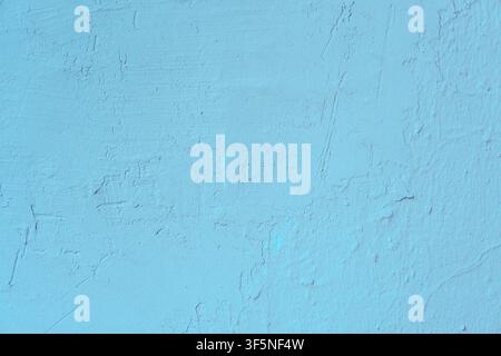 Light blue painted stucco wall with uneven surface reliefs and fine vertical cracks. Minimalist sky-colored background featuring weathered cement maso Stock Photo
