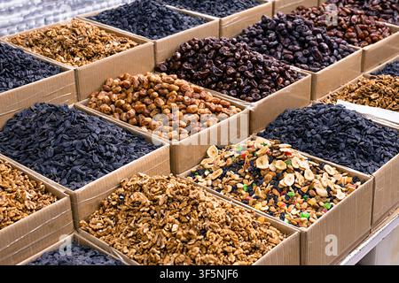 Dried fruits and nuts displayed in cardboard boxes at an oriental bazaar in Bukhara, Uzbekistan. Assortment includes raisins, dates, walnuts, and trai Stock Photo