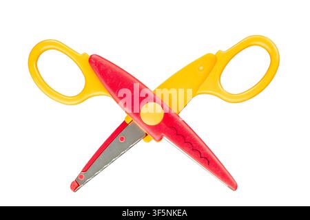 Children's scissors with a figured blade that create a neat wavy cut (zigzag) on ​​paper or cardboard on a white background, close-up. Stock Photo