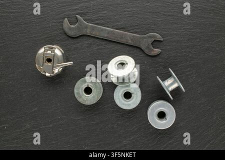 Metal bobbins for sewing machine threads on slate stone, macro. Top view. Stock Photo