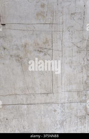 Concrete wall background with deep cracks and incised geometric lines. Aged cement surface with rough gray textures and industrial grunge patterns. Stock Photo