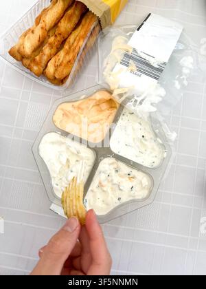 Dipping a crisp into a dip in a four pack of dips, a common snack at a party Stock Photo