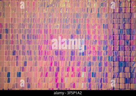 A textured mosaic wall showcases a mesmerizing blend of pink, purple, and blue tiles. Light reflects off the surface, creating an engaging visual expe Stock Photo