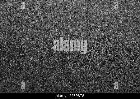 Photo texture of a black powder coating surface showing rough grain, fine detail and abstract monochrome pattern ideal for backgrounds, design overlay Stock Photo