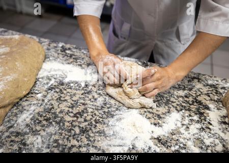 Baker kneading sourdough bread dough on a stone surface Stock Photo