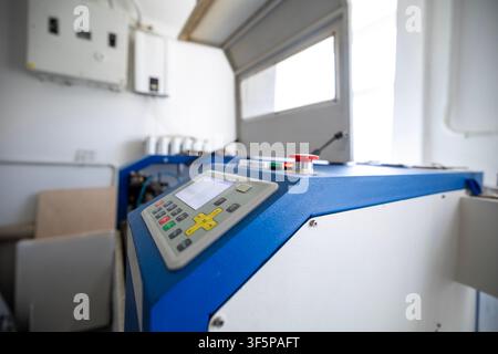Industrial cnc laser cutting machine with control panel interface and safety emergency stop button in a bright workshop space electrical boxes mounted Stock Photo