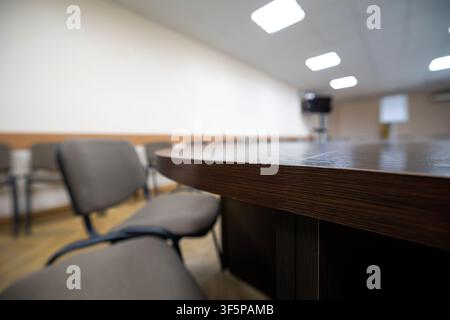 Modern meeting room with a wooden table and several chairs arranged for a professional discussion in an empty bright workspace ceiling lighting and wh Stock Photo