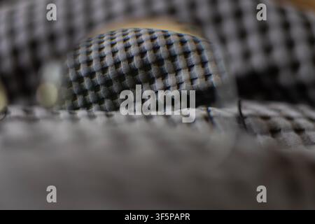 Close up macro textured grey synthetic fabric with repeating grid pattern sharp details in center focus and soft blur on the edges creating depth in t Stock Photo