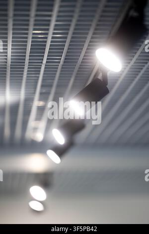 Modern ceiling lighting system with bright spotlights mounted on a suspended metallic grid structure in a contemporary architectural interior space sh Stock Photo