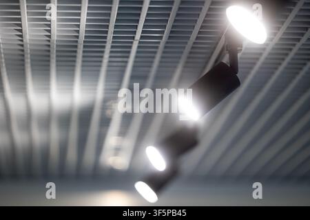 Modern ceiling spotlights installed on a metal grid structure illuminate a bright indoor commercial area while casting soft shadows and creating a pro Stock Photo