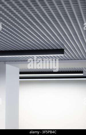 Modern office ceiling with grid panels and minimalist light fixtures Stock Photo
