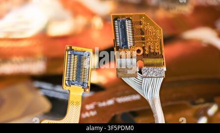 Closeup of electronic flex connectors of cellphone, tablet or computer on blur background. Yellow flexible flat cable and orange bendy circuit board. Stock Photo