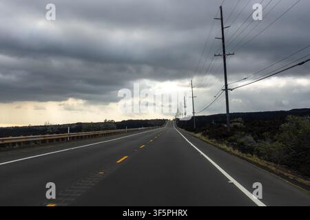 Empty asphalt road leading through volcanic lava fields on the Big Island Hawaii Stock Photo