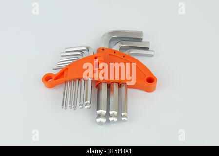 Set of metal hex keys in different sizes arranged in a bright orange plastic holder on a light background Stock Photo