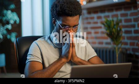 Worried anxious African American business man thinking looking at laptop at evening office pensive troubled businessman male guy manager professional Stock Photo