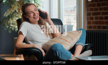 Caucasian middle-aged woman relaxing smiling answering mobile phone call happy talking at home enjoying pleasant conversation indoors European Stock Photo