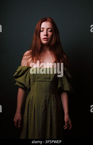 Red Haired Woman in Olive Green Dress With Closed Eyes Evoking Calmness Introspection and Quiet Serenity Stock Photo