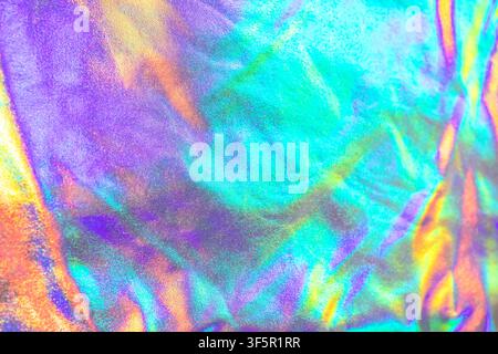 Iridescent holographic texture with vibrant rainbow color and reflective foil creating abstract shimmering patterns Stock Photo