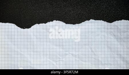 Ripped piece of squared paper on a black background, white crumpled texture, isolated centered composition, abstract banner. Stock Photo